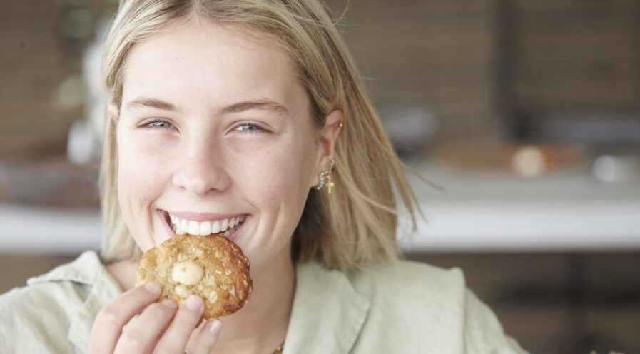 Girl biting into a macadamia cookie